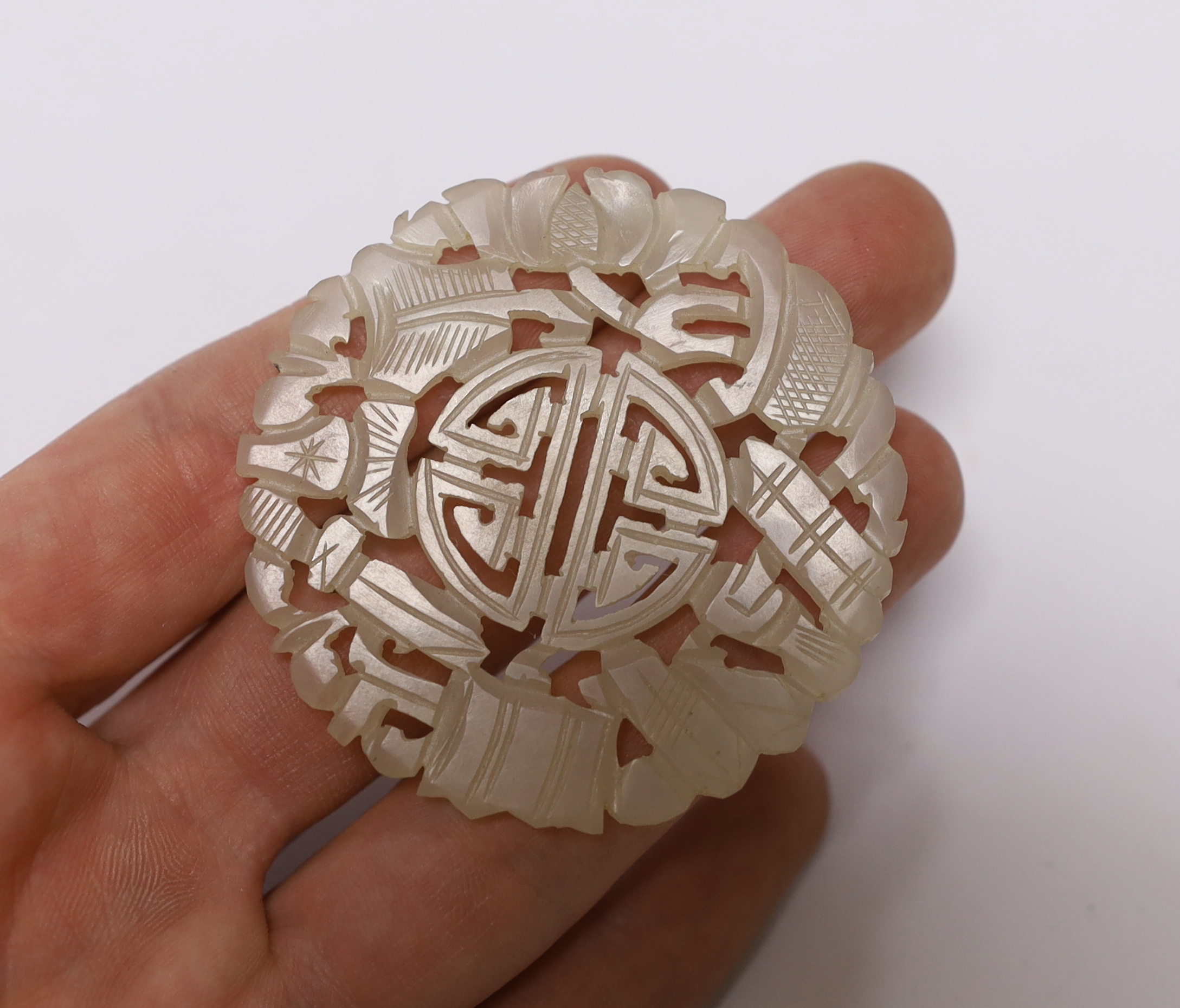 A Chinese carved pale celadon disc, 5.5cm in diameter